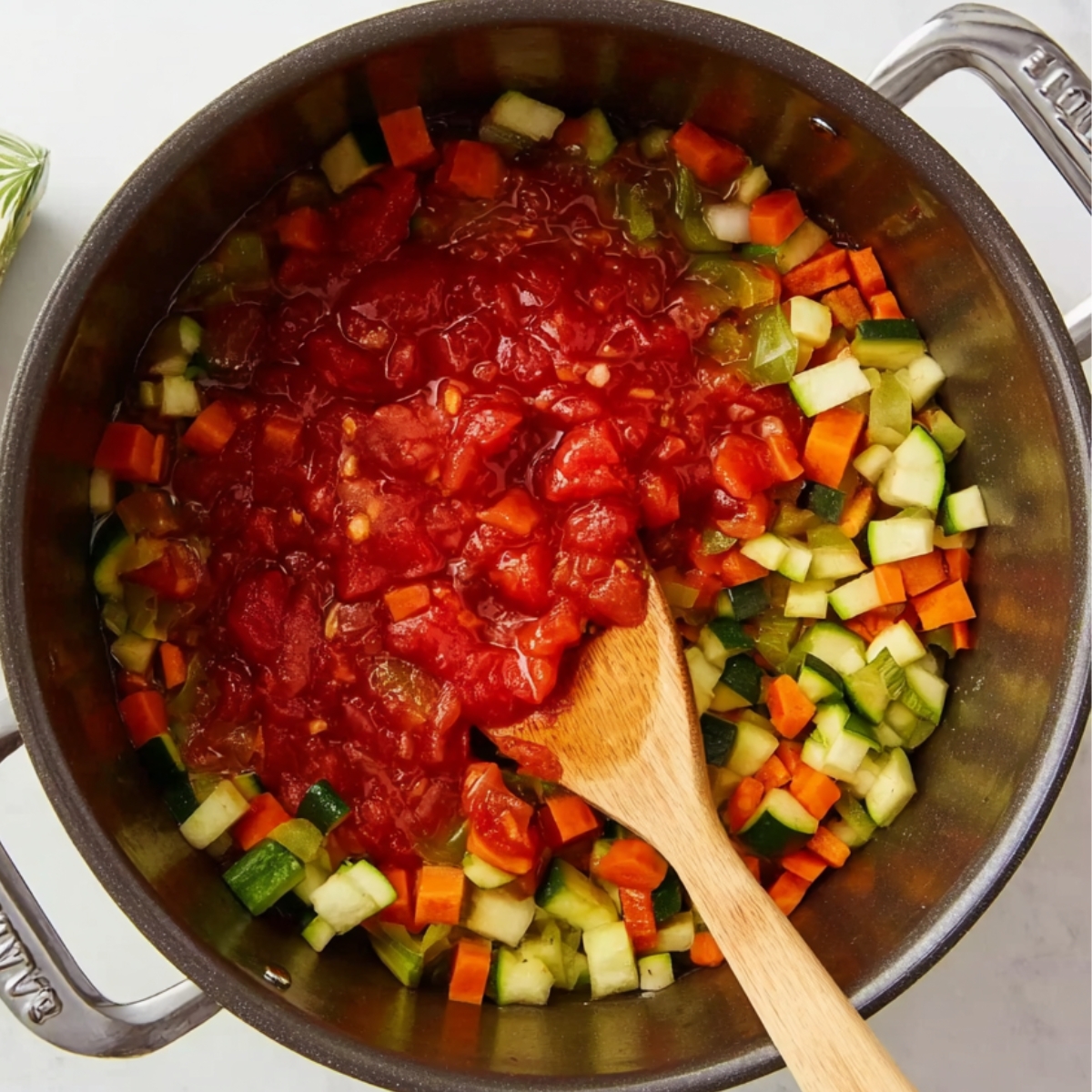Easy Minestrone Soup Recipe | Better Than Restaurant 11 Chopped tomatoes added to a pot of diced zucchini, carrots, celery, and onions while making minestrone soup.