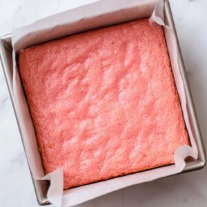 Strawberry Brownies Recipe | Soft, Pink & Ready in 30 Min 18 Freshly baked strawberry brownies in a square pan, showing a soft pink surface after baking.