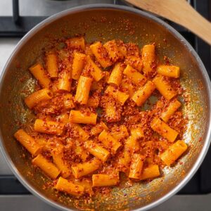 Best Gochujang Pasta Recipe | Creamy & Spicy in 20 Minutes 19 Rigatoni pasta coated in a creamy gochujang sauce inside a pan, topped with chili flakes, overhead cooking shot.