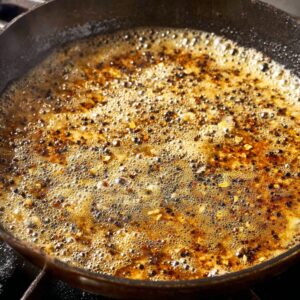 Easy Peppercorn Sauce Recipe | Ready in 20 Minutes 18 A bubbling peppercorn sauce in a skillet, with hints of golden brown and black pepper floating in the rich, aromatic sauce.