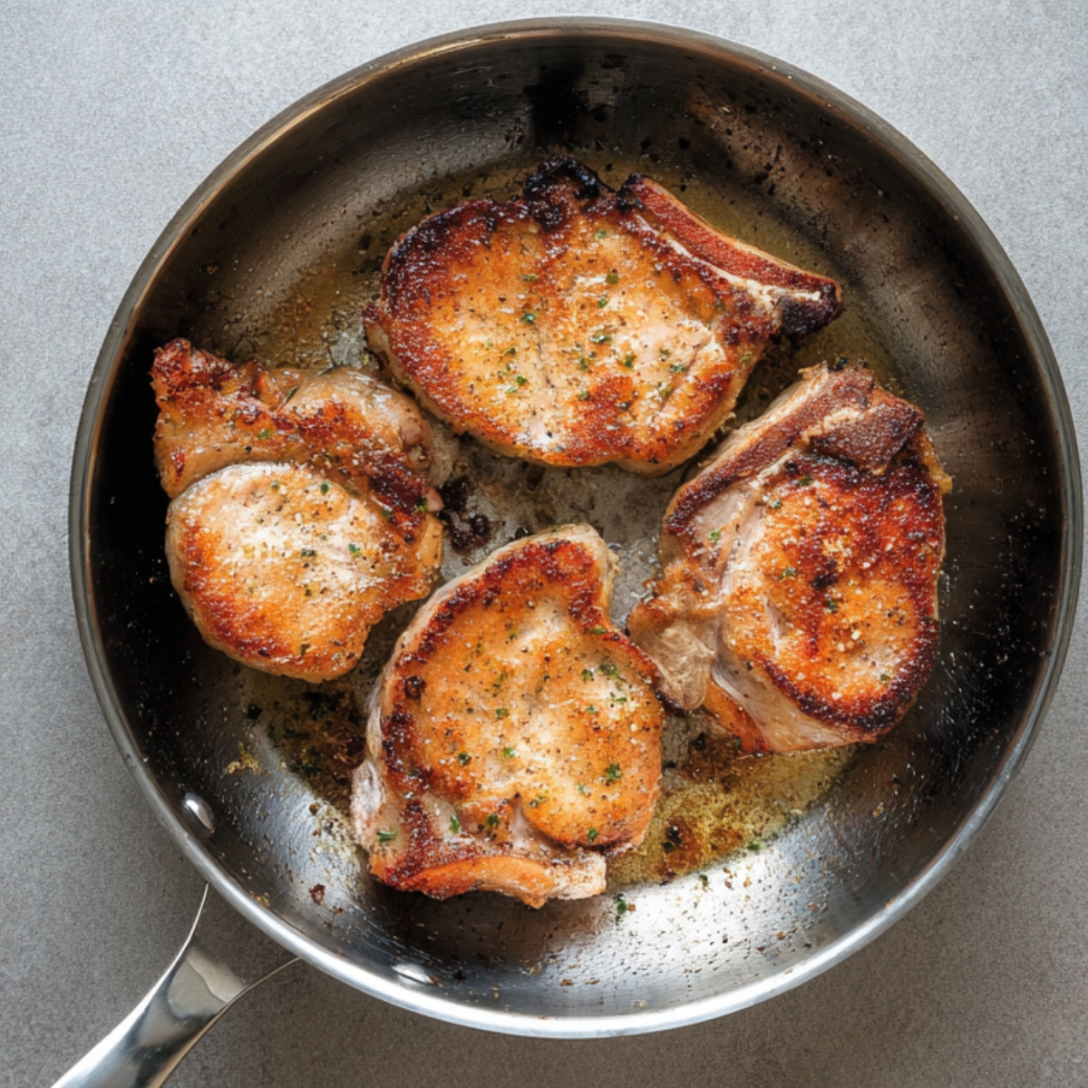 Easy Pineapple Pork Chops Recipe | Ready in 20 Minutes 11 Pork chops browning in a stainless steel skillet, showing a golden crust during the cooking process.