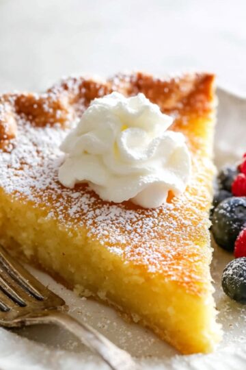 Buttermilk Chess Pie Recipe | 8 Simple Ingredients 20 Buttermilk Chess Pie Slice of buttermilk chess pie topped with whipped cream and served with raspberries and blueberries on a white plate.
