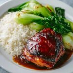 Char Siu Chicken Glazed char siu chicken thigh served with steamed white rice and sautéed bok choy on a white plate, coated in sticky red barbecue sauce.