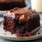 Chocolate Mayonnaise Cake A slice of moist, chocolate cake topped with a generous layer of chocolate frosting, served on a plate with a fork beside it.