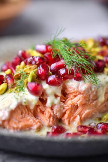 Christmas Salmon Recipe | Ready in 40 Minutes 22 Christmas Salmon Recipe Extreme close-up of flaky baked salmon texture topped with creamy sauce, pomegranate arils, pistachio pieces, and fresh dill, shallow depth of field, soft bokeh background, luxurious food photography, vibrant colors, high detail.”