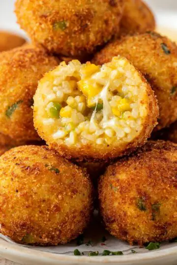 Delicious Fried Rice Balls Recipe In 3 Steps 5 Fried Rice Balls Crispy fried rice balls stacked on a plate, one cut open revealing melted cheese and rice filling, golden crunchy crust, shallow depth of field, soft natural light, high-detail food photography, appetizing close-up shot