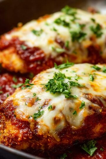 Easy Keto Chicken Parmesan Recipe 8 Keto Chicken Parmesan Baked chicken parmesan with melted cheese and tomato sauce, garnished with fresh parsley and served on a white dish.