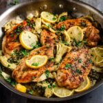 Lemon Artichoke Chicken Golden brown chicken breasts garnished with lemon slices and parsley, cooked with artichoke hearts and capers in a pan