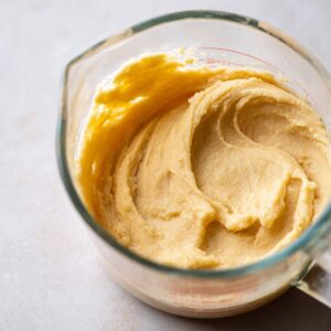 Lemon Cinnamon Rolls Recipe | Soft, Tangy & Easy 17 Close-up food photograph of creamy lemon sugar filling inside a glass measuring cup, smooth thick texture, soft neutral background, clean baking prep style, natural light, ultra detailed, realistic food photography