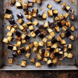 Healthy Sicilian Caponata Recipe | Sweet & Sour Eggplant Dish 16 “Roasted eggplant cubes spread on a baking sheet for preparing Sicilian caponata.”