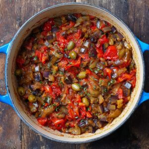 Healthy Sicilian Caponata Recipe | Sweet & Sour Eggplant Dish 17 “Homemade Sicilian caponata simmering in a blue Dutch oven with eggplant, tomatoes, celery, and olives.”