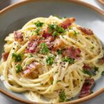 Spaghetti Carbonara Plated spaghetti carbonara with crispy bacon, parsley garnish, and black pepper.
