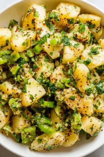 Turkish Potato Salad (No Mayo!) | 6 Easy Steps 1 Turkish potato salad Overhead view of Turkish potato salad in a white bowl, featuring tender potatoes mixed with green onions, parsley, spices, and olive oil on a marble background.