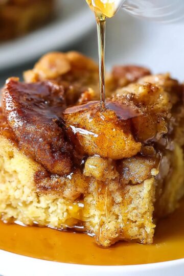 The Best Crockpot French Toast Recipe 15 crockpot french toast A serving of slow-cooked French toast casserole, drizzled with syrup on a white plate. The French toast is golden-brown with cinnamon and caramelized sugar on top, showing a close-up shot of the rich texture and sweetness.
