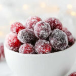 sugared cranberries A white bowl filled with sugar-coated cranberries, styled on a bright, soft background.