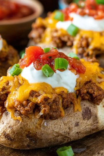 Taco Potatoes Recipe | Double Stuffed & Cheesy 23 taco potatoes High-quality food photography of taco stuffed baked potatoes topped with seasoned ground beef, melted cheddar cheese, sour cream, salsa, and chopped green onions, served on a rustic wooden board, shallow depth of field, warm lighting, comfort food style, ultra realistic, Pinterest-style photography