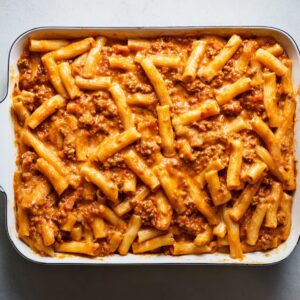 Best Baked Ziti Recipe | Feed a Crowd in Under 1 Hour 17 Top-down view of ziti pasta fully mixed with creamy tomato meat sauce in a rectangular baking dish before baking