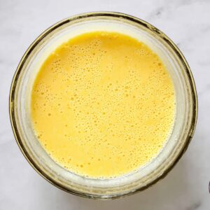 Buttermilk Chess Pie Recipe | 8 Simple Ingredients 15 Glass bowl filled with yellow pie batter, viewed from above on a light marble countertop.