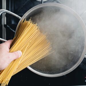 One-Pan Chicken Alfredo Recipe | Ready in 40 Minutes 17 Dry spaghetti being added to a pot of boiling water on a kitchen stove