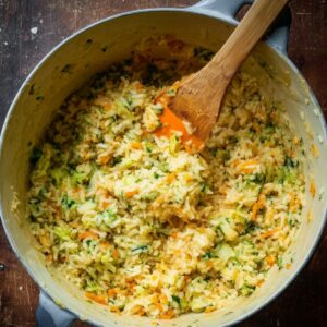 Delicious Fried Rice Balls Recipe In 3 Steps 16 Seasoned rice mixture with vegetables in a cooking pot, stirred with a silicone spatula, preparation step, overhead angle, rustic kitchen style, natural lighting, detailed texture, realistic cooking photography