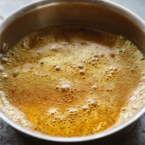 Easy Granola Recipe: Crunchy Clusters in Just 30 Minutes 16 Close-up of honey and oil mixture gently bubbling in a small saucepan, golden color, smooth texture, minimal kitchen background, natural soft lighting, realistic cooking photography