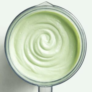 Grasshopper Drink Recipe | 4-Ingredient Frozen Cocktail 15 Top-down view of a blender jar containing a creamy pale green mint drink with a smooth spiral on the surface.