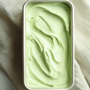 Grasshopper Drink Recipe | 4-Ingredient Frozen Cocktail 17 A rectangular container filled with a smooth, pale green frozen grasshopper drink, viewed from above on a light fabric background.