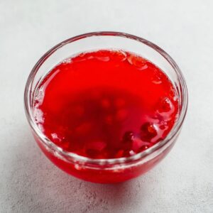 Jello Fruit Salad Recipe | Easy 10-Ingredient Classic 15 A glass bowl filled with bright red cranberry juice, showcasing its vibrant color, perfect for making fruit salads or adding to drinks.