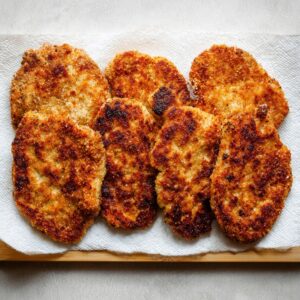 Easy Keto Chicken Parmesan Recipe 15 Golden crispy breaded chicken cutlets resting on paper towels after frying.