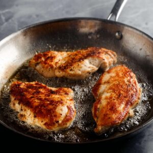 Healthy Lemon Artichoke Chicken Recipe | One-Pan Dinner 16 Chicken breasts searing in a pan with a golden brown crust