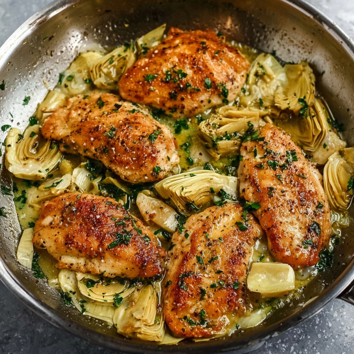 Healthy Lemon Artichoke Chicken Recipe | One-Pan Dinner 13 A close-up of perfectly cooked golden chicken breasts in a skillet with artichoke hearts, lemon slices, and herbs.