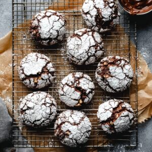 Nutella Crinkle Cookies Recipe | Soft & Fudgy 19 Nutella crinkle cookies cooling on a wire rack with cracked powdered sugar tops
