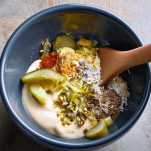 Smash Burger Tacos Recipe | Crispy & Easy in Minutes 15 A bowl filled with mayonnaise, pickles, and seasonings, being mixed to create a creamy sauce for the smash burgers or tacos.