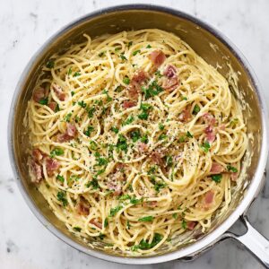 Easy Spaghetti Carbonara Recipe 18 Creamy spaghetti carbonara mixed in a stainless steel pan with bacon, black pepper, and parsley.
