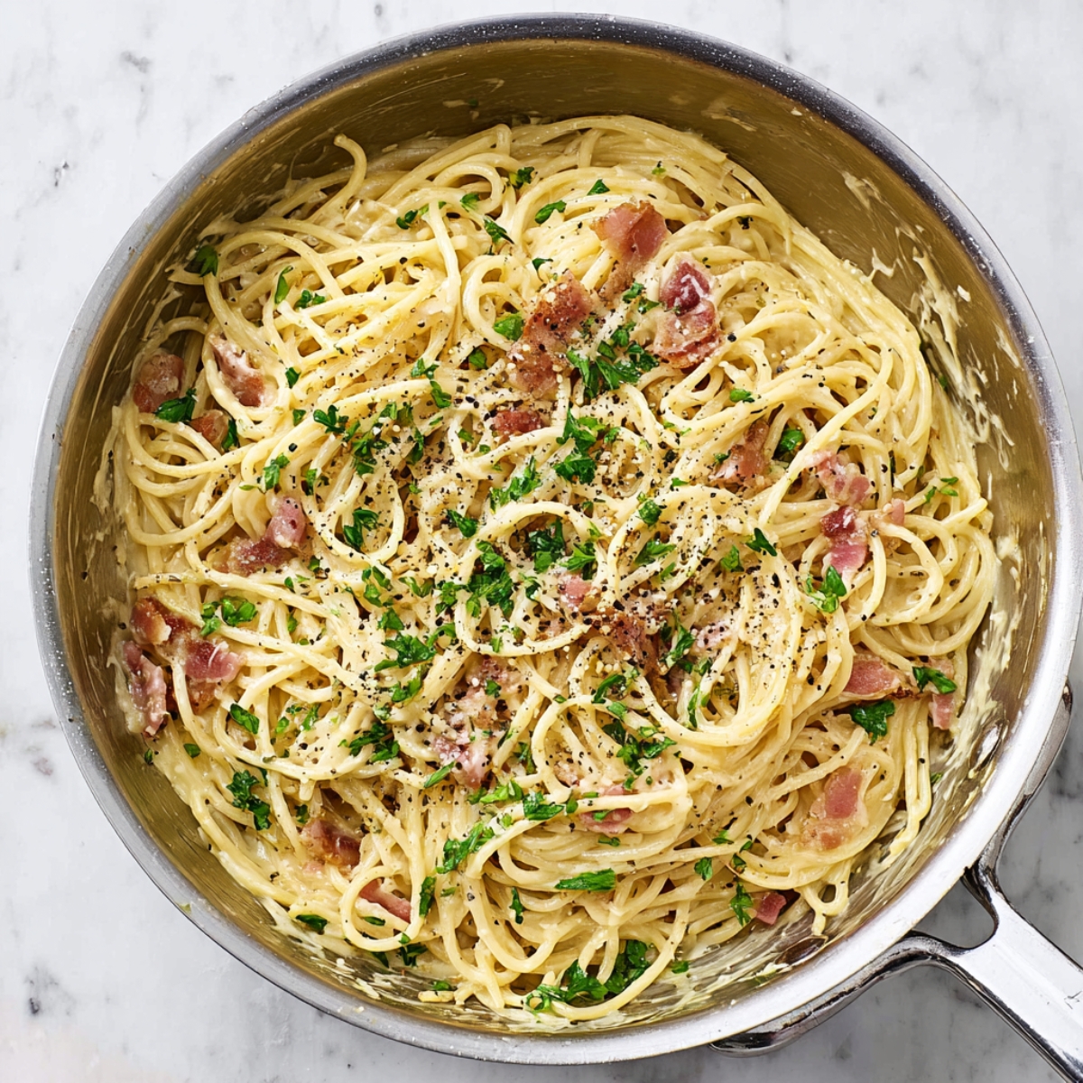 Easy Spaghetti Carbonara Recipe 13 Creamy spaghetti carbonara mixed in a stainless steel pan with bacon, black pepper, and parsley.