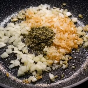 Creamy Tomato Gnocchi Recipe | Ready in 16 Minutes 15 Chopped onions sautéing in a pan with garlic and pesto added in the center.