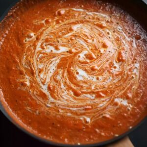 Creamy Tomato Gnocchi Recipe | Ready in 16 Minutes 16 Creamy tomato sauce with visible swirls of cream simmering in a pan.