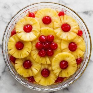 Pineapple Upside Down Cake Recipe | Old Fashioned & Easy 17 A close-up of a glass baking dish filled with a mixture of melted butter and brown sugar. The sugar is sprinkled on top, with a rich caramelized texture forming at the bottom, setting the stage for a classic pineapple upside-down cake.