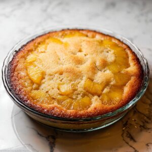 Pineapple Upside Down Cake Recipe | Old Fashioned & Easy 19 A golden-brown, freshly baked pineapple upside-down cake in a glass baking dish. The top is slightly crispy, and the edges of the pineapple are caramelized, creating a perfectly baked dessert.