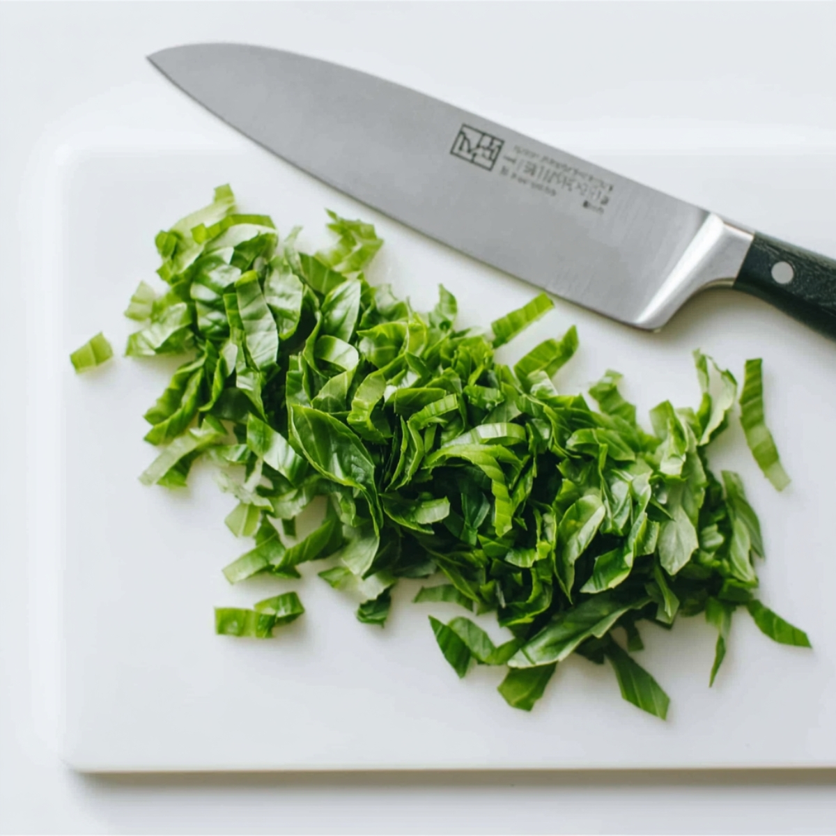 Easy Tomato Bruschetta Recipe | Ready in 37 Minutes 10 Fresh basil leaves finely sliced on a white cutting board with a chef knife