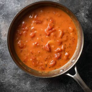 Southern tomato gravy simmering in a skillet, thick and smooth with visible tomato pieces, overhead view.