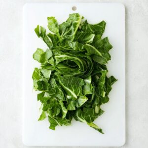 Best Turnip Greens Recipe - Smoked Turkey & Pot Liquor 16 Fresh collard greens sliced into thin ribbons on a white cutting board.