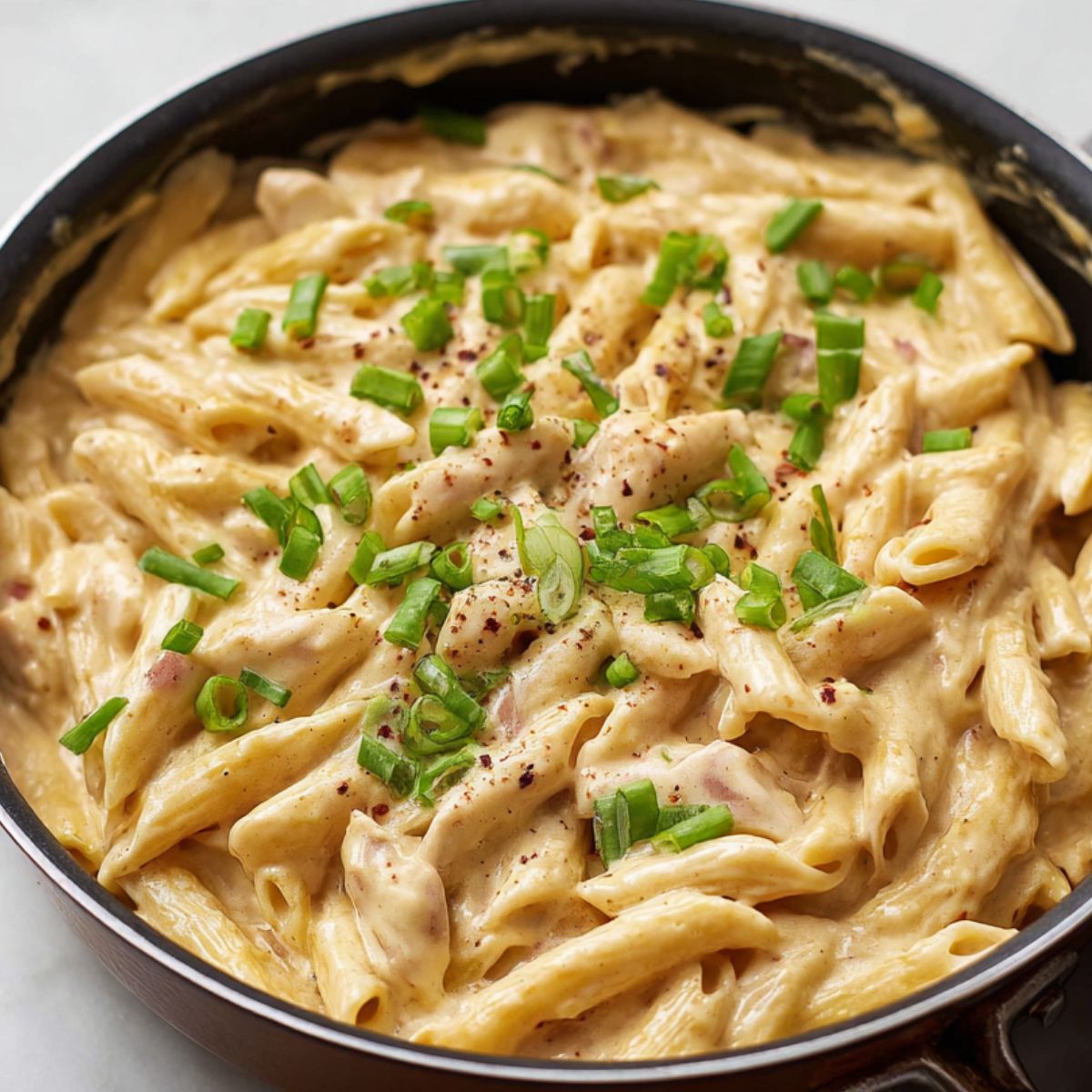 Buffalo Chicken Pasta in a creamy sauce, garnished with fresh green onions, adding a burst of color and freshness to the dish.
