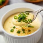 Chinese Steamed Eggs A spoonful of the steamed eggs, garnished with some green onions, showing the smooth texture of the dish.