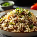 Dirty Rice Close-up food photography of a bowl of rice mixed with ground beef and finely chopped green peppers, Moroccan-style rice dish, served in a ceramic bowl, soft natural lighting, cozy kitchen atmosphere, high detail, realistic texture, shallow depth of field."