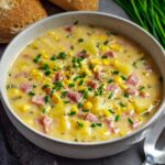 Ham and Potato Soup A bowl of finished creamy ham, potato, and corn chowder garnished with chopped chives, ready to be served.