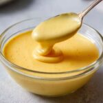 Hollandaise Sauce A rich and creamy hollandaise sauce in a glass bowl, with a spoon dripping some of the golden sauce.