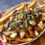Poutine Recipe A serving of poutine with crispy fries, mushroom gravy, and cheese curds, garnished with fresh herbs.