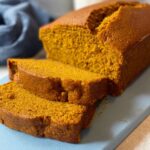 Pumpkin Bread A loaf of homemade pumpkin bread sliced on a cutting board, showing a moist and fluffy interior with a beautiful orange color.