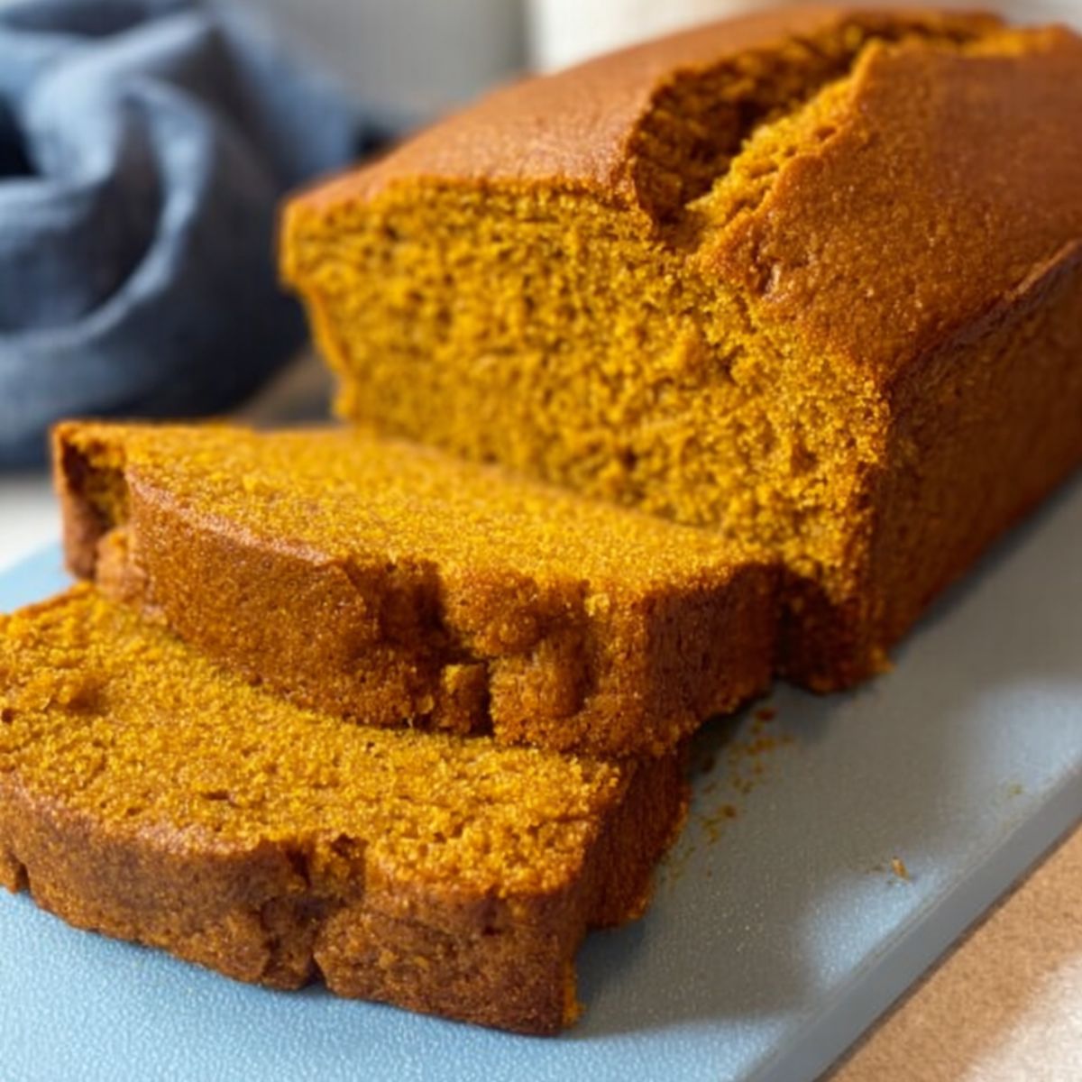 The Best Pumpkin Bread Recipe 9 Pumpkin Bread A loaf of homemade pumpkin bread sliced on a cutting board, showing a moist and fluffy interior with a beautiful orange color.